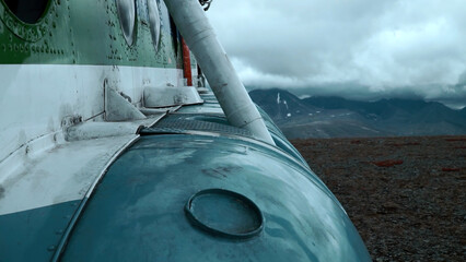 Close up of old rusty airplane on a hill top. Clip. Aircraft exterior details with heavy clouds and mountains on the background.