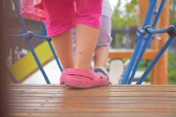 A little girl in pink shoes is standing on a wooden deck