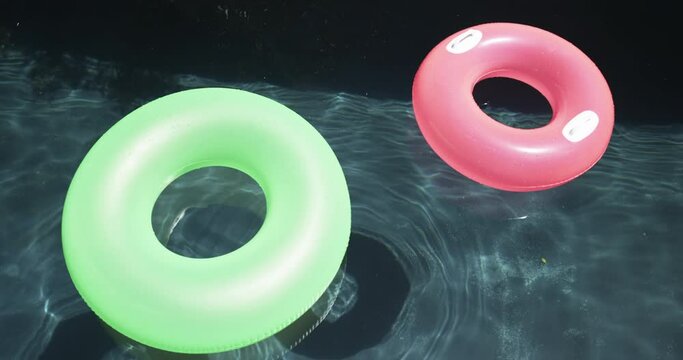 Two colorful swim rings float on a pool's surface