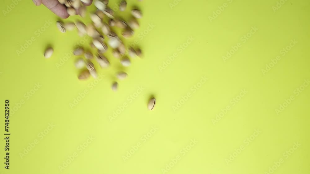 Poster top view of pistachios nuts dropping on yellow background  - Posters