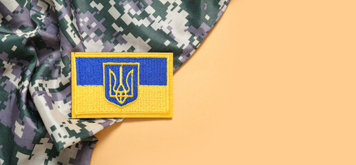 Military badge of Ukrainian army with trident and soldier's uniform on beige background with space...