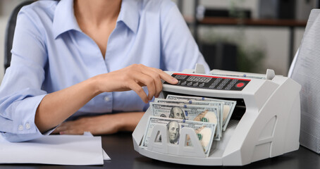 Female bank manager using cash counting machine in office, closeup