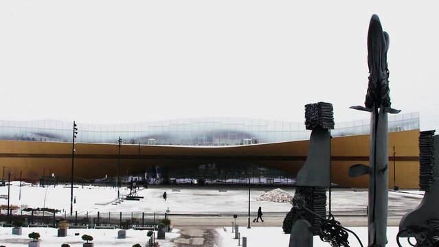 Snow-covered Helsinki Central Library Oodi, modern architecture, winter day, statues in foreground