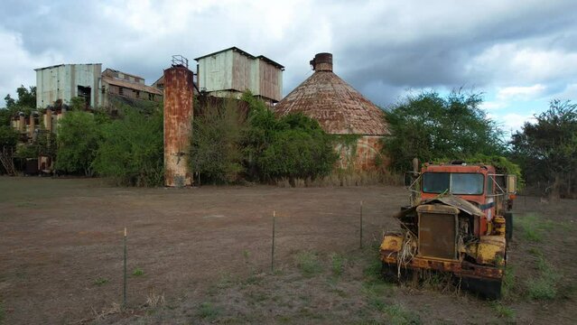 Old truck with abandoned Koloa sugar mill Kauai, Hawaii in background, circle drone shot