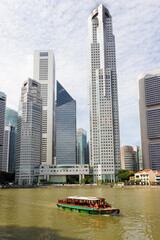 Fototapeta premium Bumboat on the Singapore river with the tall buildings of the financial district behind