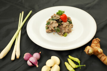 Fish Cakalang Green Chilli. Indonesian tradition green chilli saute with fish in white plate. Isolated on black background. Selective focus.
