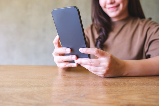 Closeup image of a young woman holding and using smart phone
