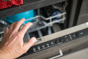 a hand opening a dishwasher, indoor closeup