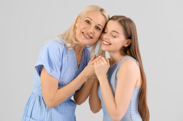 Young woman with her mother on grey background