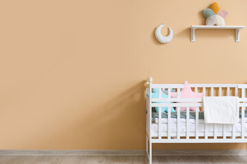 Interior of children's room with crib near beige wall - obrazy, fototapety, plakaty