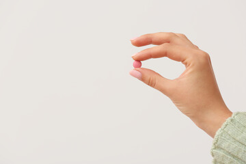 Woman holding pink pill on white background