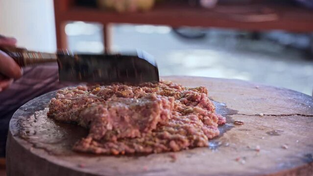 a Person is do Chopping Raw Pork Meat with Blakas, a Traditional Balinese Knife on the Wooden Board