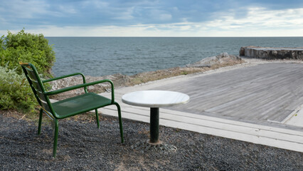 Green chair and table on the beach with the sea in the background