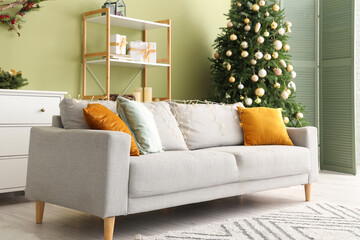 Stylish interior of modern living room with comfortable sofa and Christmas tree
