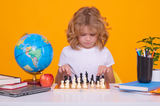 Child with chess on yellow isolated studio background. Little kid play chess. Thinking child. Chess game for kids. Intelligent, smart and clever school boy.