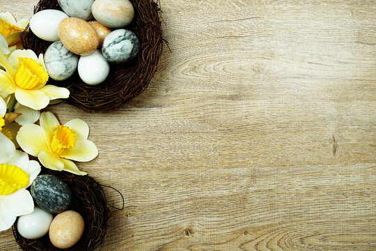 Easter background with eggs and flowers bouquet top view on wooden background