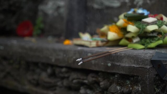 An image showing traditional offerings including food, flowers, and lit incense sticks, possibly as part of a cultural or religious ceremony.