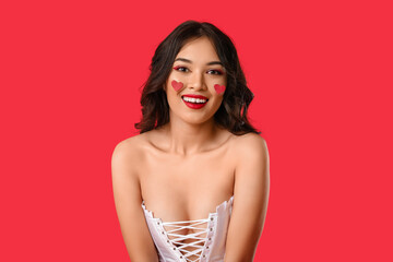 Beautiful young cute Asian woman with paper hearts on red background. Valentine's Day celebration