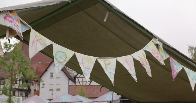 A chain of pennants with the letters "Kolping" hangs from a tent in a tent camp