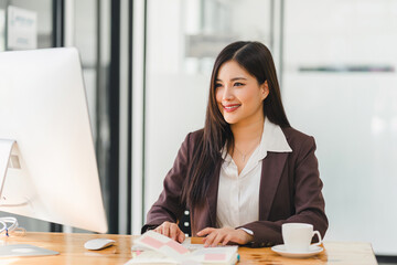 Asian professional businesswoman working on desktop computer in a corporate office.