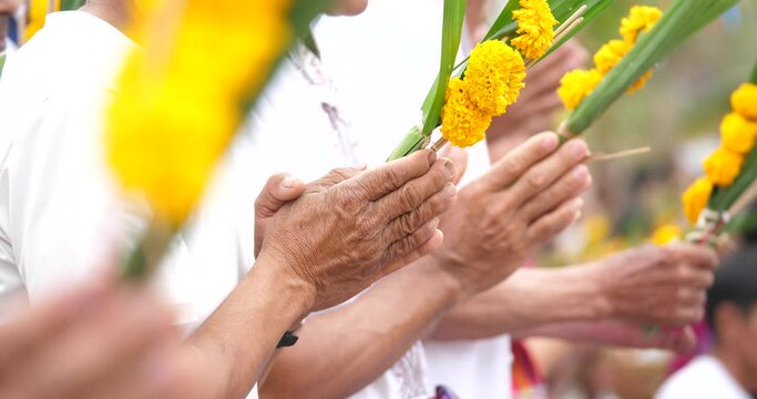 A group of people to pay respect, a group of people are performing a Buddhist ceremony, the hands of an elderly person are worshiping, 