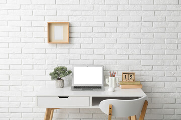 Stylish workplace with laptop and houseplant near white wall