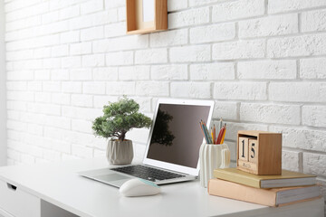 Stylish workplace with laptop and houseplant near white wall - Powered by Adobe