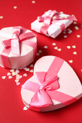 Beautiful gift boxes with confetti on red background. Valentines Day celebration