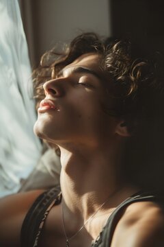 Retrato de un hombre joven  descansando y tomando el sol frente a una ventana. Descanso y salud