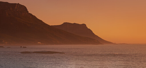 Sea, sunset and mountain on island, paradise and tourist destination for summer vacation in nature. Rocks, ocean and color in sky in cape town, peace and outdoor travel of sustainable environment