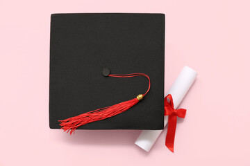 Graduation hat and diploma on pink background