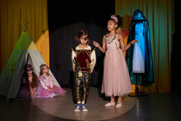 Full length portrait of young boy and girl wearing costumes acting on stage in school play...