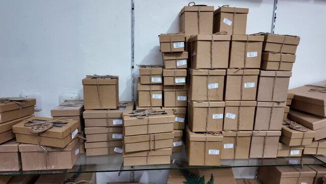 Stack of various cardboard boxes on a hanging rack in a packaging shop. Pile of carton giftbox with natural rope straps.