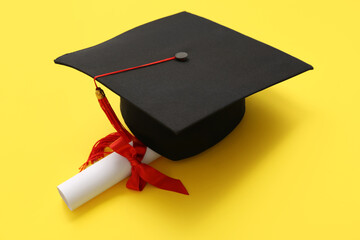Graduation hat with diploma on yellow background