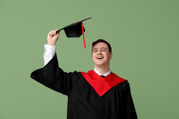 Male graduating student with mortarboard on green background