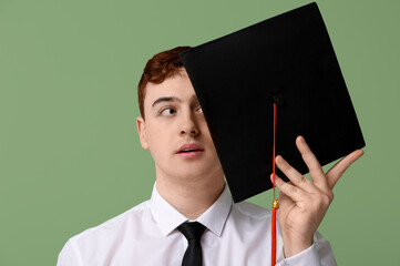 Male student with mortar board on green background