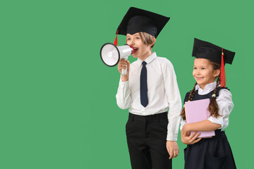 Little children in graduation hats with books shouting into megaphone on green background. End of school year