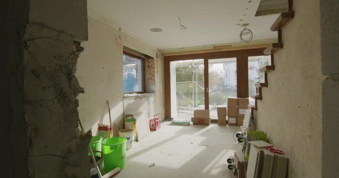 Wide shot of a construction site in a german one family house, a lot of tools and bags on the ground. Sun shining into the room.