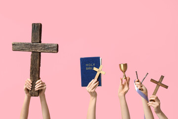 Female hands with wooden crosses, Holy Bible and nails on pink background. Good Friday concept