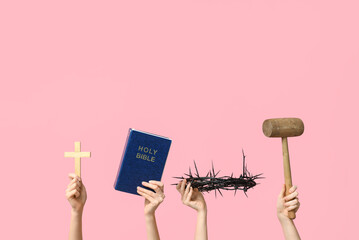 Female hands with Holy Bible, crown of thorns, cross and mallet on pink background. Good Friday...