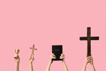 Female hands with wooden crosses, cup and holy Bible on pink background. Good Friday concept