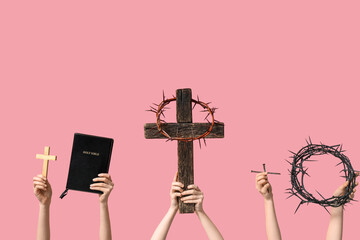 Female hands with wooden crosses, Holy Bible and crowns of thorns on pink background. Good Friday...