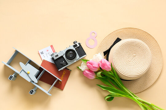 Composition with stylish hat, photo camera toy plane and tulip flowers on color background. International Women's Day