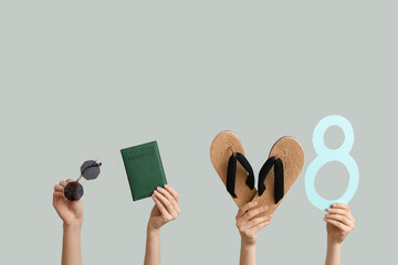 Female hands with paper figure 8, flip-flops, passport and sunglasses on grey background....
