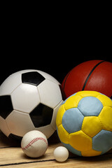 Set of various sport balls on wooden floor on black background