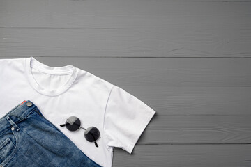 Cotton T-shirt and jeans on gray background top view
