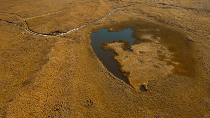 Idyllic countryside landscape with tiny lake in dried yellow field. Clip. Autumn valley and sea...