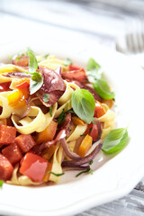 Pappardelle Pasta with Vegetables and fresh Basil and Ham on bright wooden Background. Close up.	