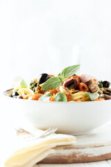 Pappardelle Pasta with cherry tomatoes, red onion and fresh basil on white wooden background.	