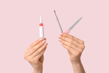 Female hands with cuticle oil pen, pusher and nail file on pink background - obrazy, fototapety, plakaty